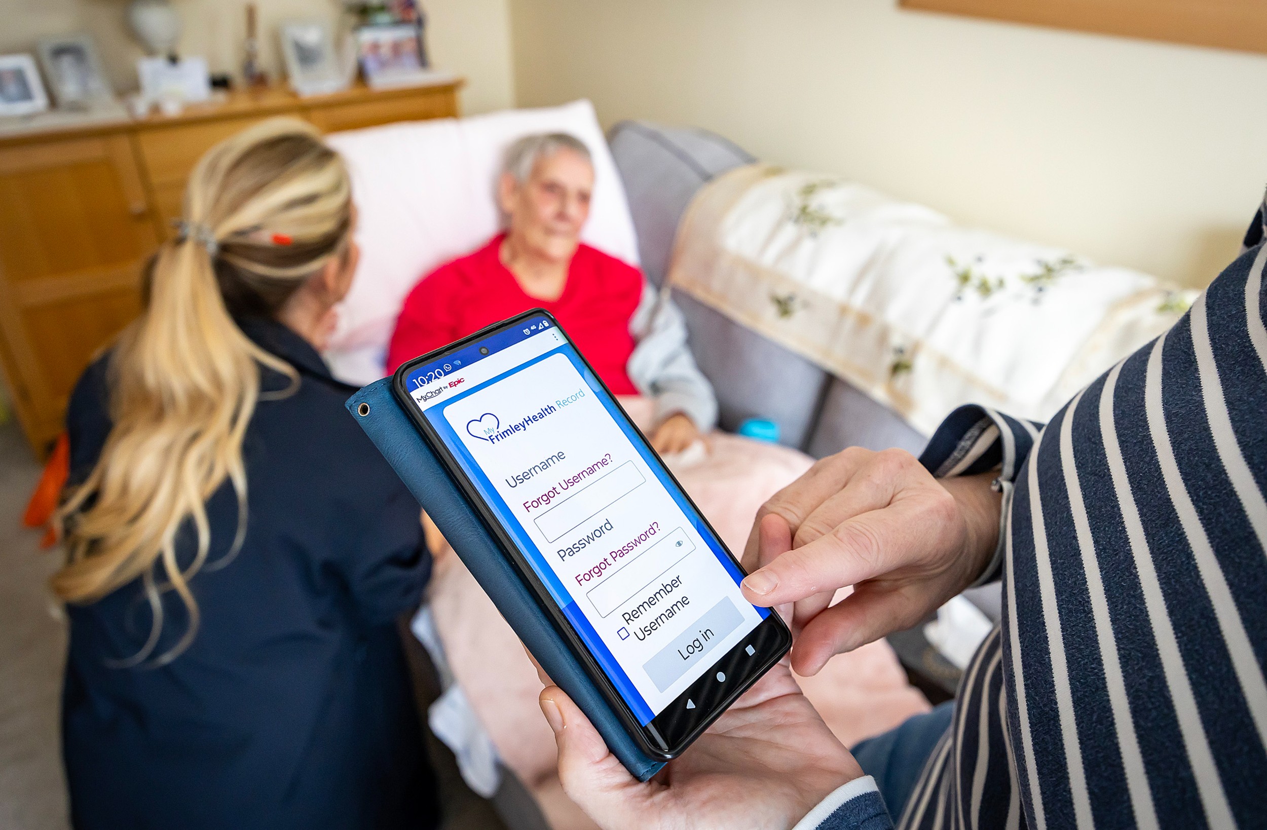 A relative logs in to MyFrimleyHealth Record while a patient receives care in bed from a community nurse
